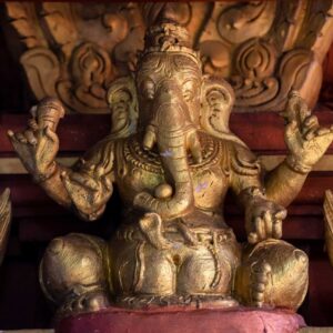 Intricately carved golden Ganesha statue set in a traditional temple environment, evoking spirituality.
